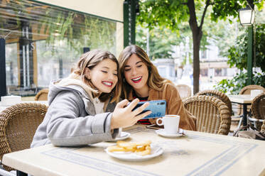 Zwei glückliche junge Frauen machen ein Selfie in einem Straßencafé - DGOF00557