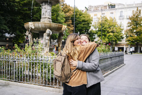 Two happy young women hugging in the city stock photo