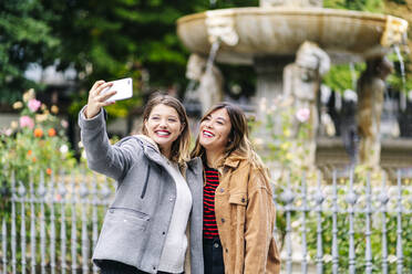 Zwei glückliche junge Frauen machen ein Selfie in der Stadt - DGOF00568