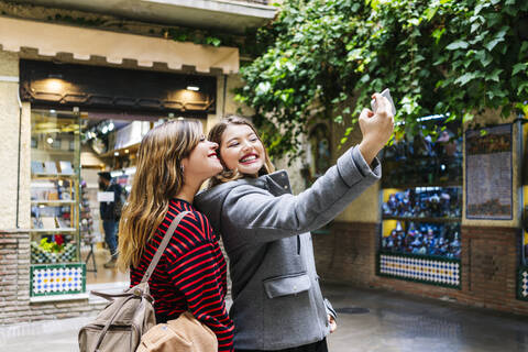 Zwei glückliche junge Frauen machen ein Selfie in der Stadt, lizenzfreies Stockfoto