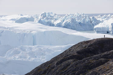 Mann auf Klippe mit Blick auf die majestätischen polaren Gletscher Grönlands - HOXF05715