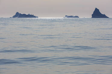 Icebergs in distance on sunny tranquil blue Atlantic Ocean Greenland - HOXF05758