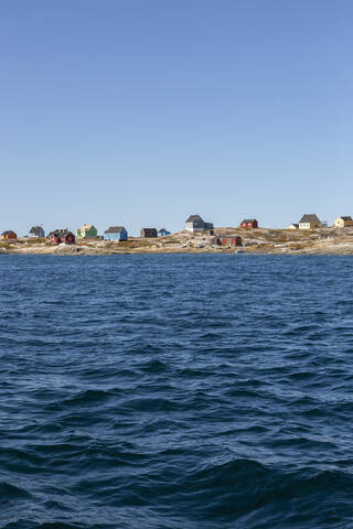 Houses on sunny remote ocean coastline Disko Bay West Greenland stock photo