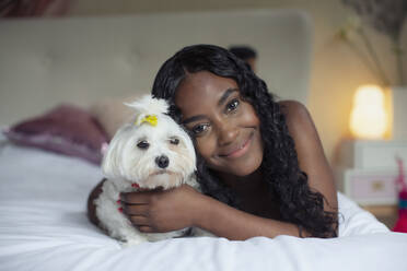 Portrait happy young woman with dog on bed - HOXF05843