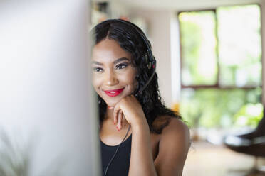 Young woman with headset working from home at computer - HOXF05849