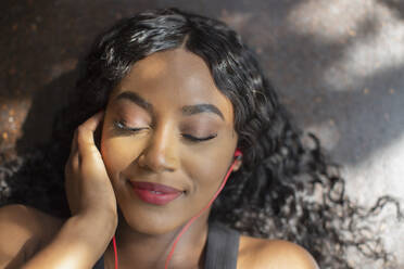 Gelassene junge Frau, die mit Kopfhörern Musik hört - HOXF05871
