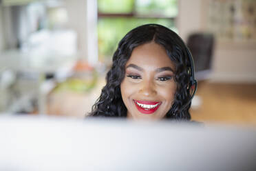 Young woman with headset working at computer - HOXF05887