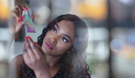 Curious young woman examining crystal - HOXF05891