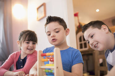 Junge mit Down-Syndrom und Geschwister spielen mit Spielzeug - HOXF05897