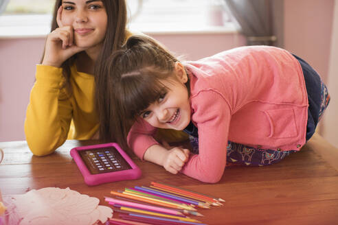 Porträt glückliche Schwestern mit digitalem Tablet auf dem Tisch - HOXF05914
