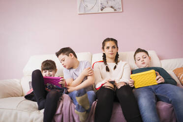 Mädchen und Bruder mit Down-Syndrom benutzen digitales Tablet auf dem Sofa - HOXF05936