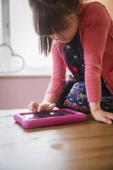 Mädchen benutzt digitales Tablet am Tisch - HOXF05956