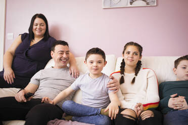 Glückliche Familie entspannt sich auf dem Wohnzimmersofa - HOXF05959