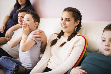 Glückliche Familie beim Fernsehen auf dem Wohnzimmersofa - HOXF05960