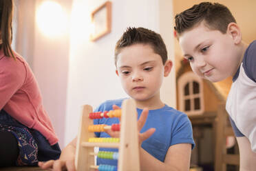 Junge mit Down-Syndrom und Bruder spielen mit Spielzeug - HOXF05971