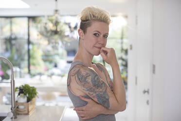 Porträt selbstbewusste Frau mit Tattoos in der Küche - HOXF06015