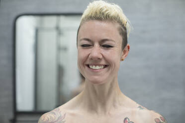 Portrait happy carefree woman with tattoos laughing in bathroom - HOXF06024