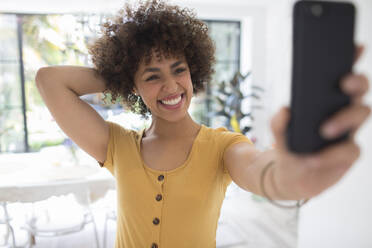 Glückliche selbstbewusste junge Frau, die ein Selfie mit ihrem Smartphone macht - HOXF06033