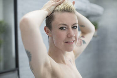 Portrait confident beautiful woman with tattoos in bathroom - HOXF06041