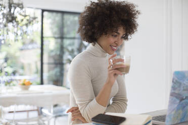 Young female freelancer drinking coffee at laptop - HOXF06052