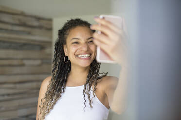 Glückliche junge Frau nimmt Selfie mit Kamera-Handy - HOXF06065