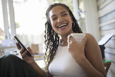 Portrait glückliche junge Frau mit Smartphone und Tee lachend - HOXF06077