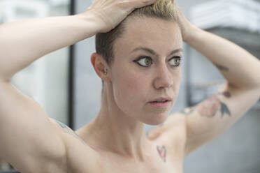 Close up woman with tattoos and hands in hair - HOXF06105