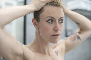 Nahaufnahme einer Frau mit Tattoos und Händen im Haar - HOXF06105