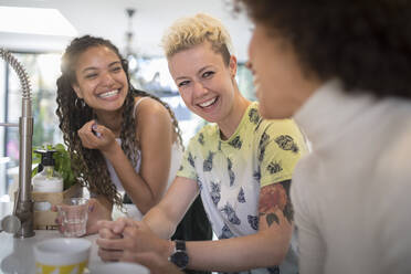 Happy young women friends laughing and talking in kitchen - HOXF06111