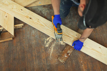Zimmermann schneidet Holz mit Säge auf der Baustelle - HOXF06134