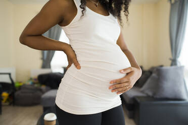 Junge schwangere Frau hält Bauch - HOXF06160