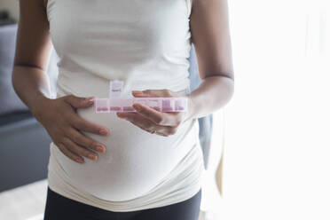 Close up pregnant woman with pill box taking vitamins - HOXF06163