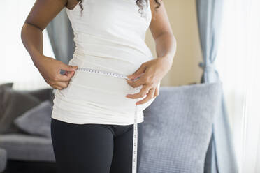 Pregnant woman measuring stomach with tape measure - HOXF06172