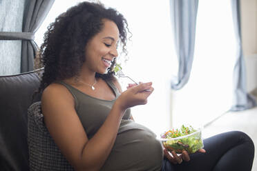 Glückliche junge schwangere Frau isst Salat - HOXF06176