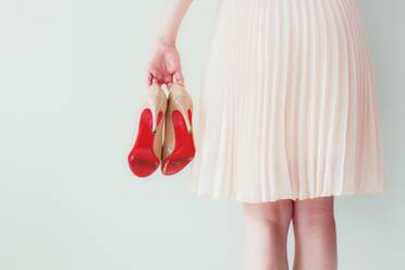 Rear View Of Woman Holding High Heels Against Wall - EYF01527