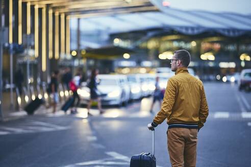 Rear View Of Mid Adult Man With Luggage Standing On Street At Airport - EYF01630