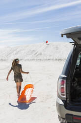Teenager-Mädchen mit einem Schlitten auf weißen Sanddünen - MINF14275