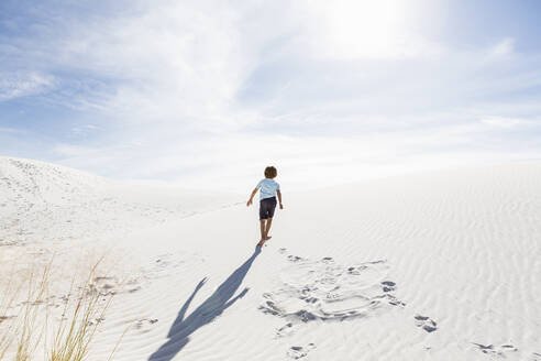 A young boy climbing up white sand dune - MINF14287