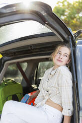 Ein junges Mädchen auf dem Rücksitz eines Geländewagens mit Gepäck - MINF14333