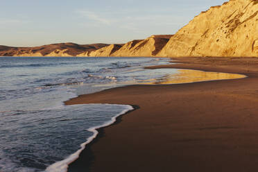 Strand in der Morgendämmerung, mit steilen Klippen und Felsen. - MINF14372