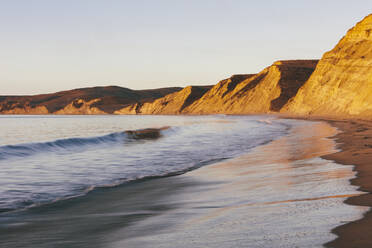 Steep cliffs and beach with surf at dawn - MINF14375