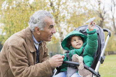 Großvater mit neugierigem Enkelsohn im Kinderwagen - CAIF24514