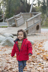 Lächelndes Kleinkind, das im Herbst im Park spazieren geht - CAIF24530