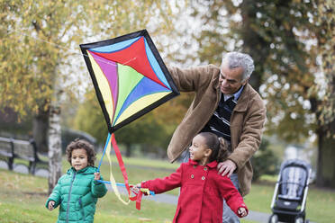 Großvater und Enkelkinder lassen im Herbst im Park einen Drachen steigen - CAIF24531