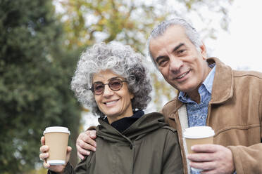 Porträt eines lächelnden, selbstbewussten älteren Paares beim Kaffeetrinken - CAIF24533