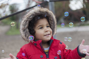 Playful toddler boy playing with bubbles - CAIF24545