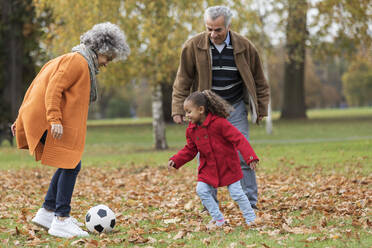 Großeltern spielen Fußball mit Enkelin im Herbst Park - CAIF24550