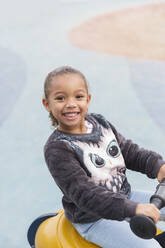 Portrait smiling, confident girl playing on playground - CAIF24558