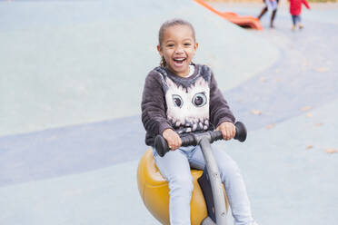 Porträt lächelndes, begeistertes Mädchen auf dem Spielplatz - CAIF24570