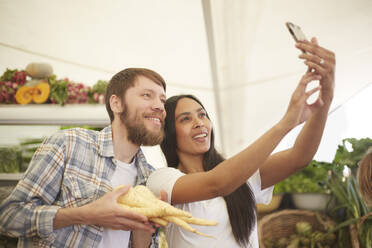 Lächelndes Paar macht Selfie auf dem Bauernmarkt - CAIF24610